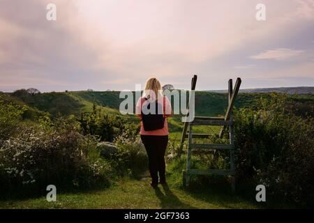 Donna che cammina su sentiero durante il tramonto in paesaggio di campagna a Skåne, Svezia. Foto Stock