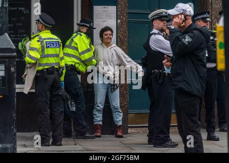 Londra, Regno Unito. 24 agosto 2021. Un manifestante viene rimosso e arrestato - la polizia inizia a rimuovere i manifestanti dal tavolo rosa sulla giunzione di Long Acre e St martins corsia - solo poche persone rimangono incatenate alle sue gambe. Estinzione la ribellione inizia due settimane di protesta, sotto l'impossibile nome della ribellione, a Londra. Credit: Guy Bell/Alamy Live News Foto Stock