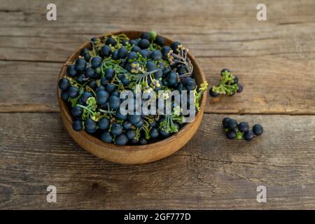 Bacche nere di ombra notturna in un piatto sul primo piano del tavolo. Ombra notturna in cucina. Cibo sano. Raccolto per cottura Foto Stock