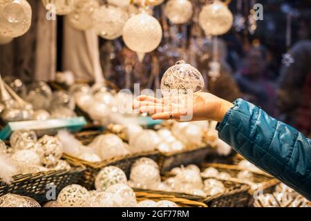 Donna che tiene baubles di Natale e decorazione in mano. Vendita di souvenir e ornamenti decorativi al mercatino di Natale di Vienna, Austria Foto Stock