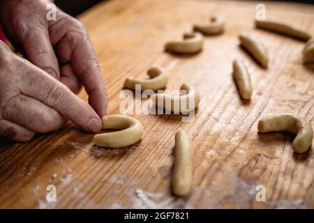 Cottura vanillekipferl. Donna anziana che forma un rotolo di vaniglia a mezzaluna da pasta di pasticceria. Fare biscotti di natale fatti in casa Foto Stock