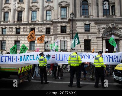 Londra, Inghilterra, Regno Unito 24 agosto 2021 giorno due della ribellione impossibile e gli attivisti del clima gallesi dicono di non nel nostro nome mentre occupano Parliament Street per chiedere all'HMRC di abbandonare il loro rapporto tossico con Barclays. I manifestanti si bloccano sui barili e bloccano la strada Credit: Denise Laura Baker/Alamy Live News Foto Stock