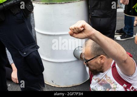 Londra, Inghilterra, Regno Unito 24 agosto 2021 giorno due della ribellione impossibile e gli attivisti del clima gallesi dicono di non nel nostro nome mentre occupano Parliament Street per chiedere all'HMRC di abbandonare il loro rapporto tossico con Barclays. I manifestanti si bloccano sui barili e bloccano la strada Credit: Denise Laura Baker/Alamy Live News Foto Stock