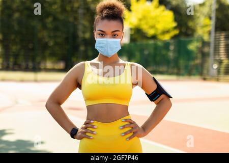 Donna che indossa maschera protettiva e sportswear posa Foto Stock