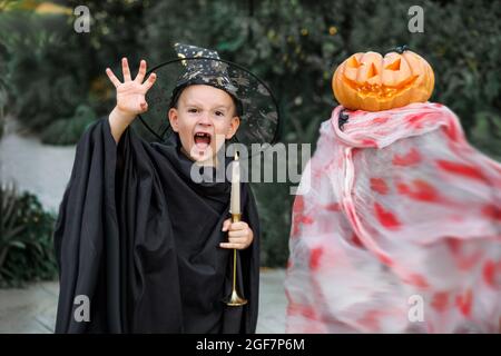 Bambino in costume di Halloween. Trucchi o delizia per i bambini. Ragazzino con zucca. Ragazzo in cappello di strega. Decorazione di festa di stagione autunnale. Fantasma esterno. Foto Stock