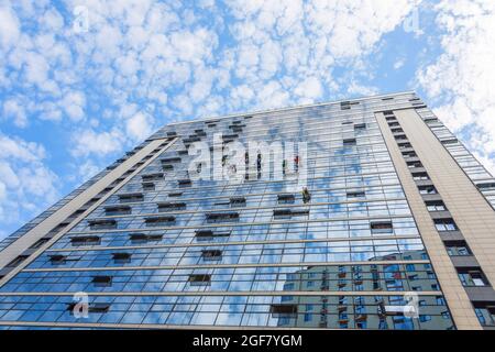 Gli scalatori puliscono le finestre dall'esterno dell'edificio lavando le vetrate della facciata di un edificio a più piani Foto Stock