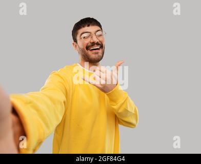 felice giovane uomo in felpa gialla che fa selfie Foto Stock