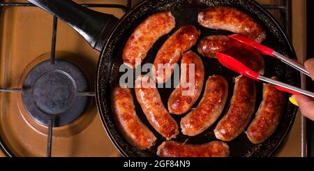 Femmina di raccolta a mano salsiccia con gli squidsda cucina da una padella, primo piano. Foto Stock