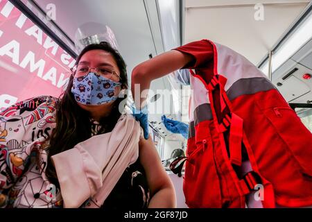 (210824) -- MANILA, 24 agosto 2021 (Xinhua) -- un operatore sanitario inocula una donna con una dose di vaccino COVID-19 all'interno di un bus di vaccinazione trasformato da un autobus aeroportuale a Manila, Filippine, 24 agosto 2021. Il Dipartimento della Salute delle Filippine (DOH) ha segnalato 12,067 nuove infezioni COVID-19 martedì, portando il numero totale di casi confermati nel paese del sud-est asiatico a 1,869,691. (Xinhua/Rouelle Umali) Foto Stock