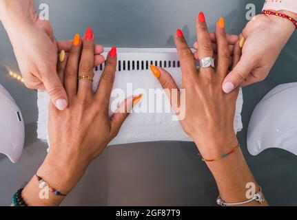 Donna che mostra il risultato finale di manicure con le sue unghie dipinte in vari colori. Foto Stock