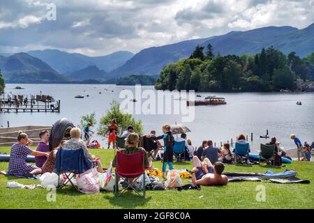 La folla si prende il sole a Crow Park sulle rive di Derwentwater nel Lake District mentre i visitatori di Cumbria sono invitati a prendere un test di flusso laterale prima di viaggiare per la contea dopo un forte aumento dei casi di coronavirus nella regione. Data foto: Martedì 24 agosto 2021. Foto Stock