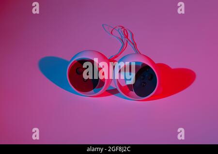 Controller di realtà virtuale per i videogame online e cloud su sfondo bianco con luce al neon. Realtà virtuale, futuro, gadget, concetto di tecnologia. Foto Stock