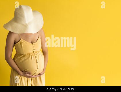 Maternità, femminilità, moda, estate calda - banner donna incinta irriconoscibile donna in bella vintage abito cappello di paglia Provenza con le mani sopra Foto Stock