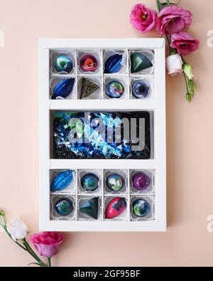 Un set di caramelle fatte a mano in confezioni festive. Design spaziale. Caramelle su sfondo chiaro e decorazioni di fiori di rosa Foto Stock
