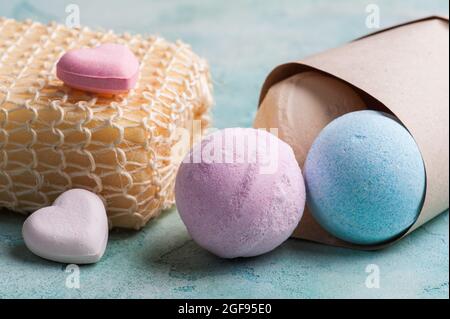 Bombe da bagno blu, vaniglia e fragola nel cono su fondo di cemento turchese Foto Stock