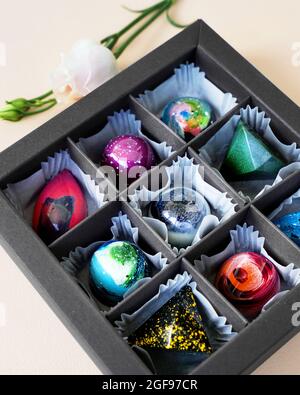 Scatola regalo nera di cioccolatini fatti a mano. Design geometrico e spaziale. Su uno sfondo chiaro. Dolci e caramelle in primo piano Foto Stock