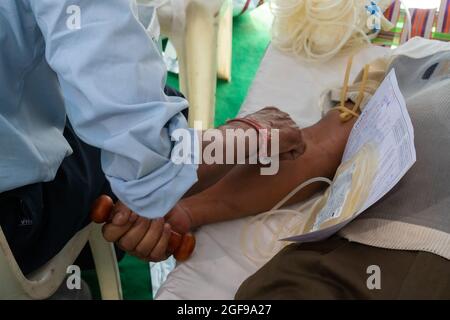 HOWRAH, BENGALA OCCIDENTALE / INDIA - 25 FEBBRAIO 2018 : Dottore maschio che raccoglie sangue da giovane volontario maschile giacente sul letto all'interno della donazione pubblica di sangue ca Foto Stock