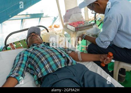 Kolkata, Bengala Occidentale, India - 25 Febbraio 2018 : persona medica maschile che raccoglie il sangue da giovane volontario maschile giacente sul letto all'interno del sangue pubblico do Foto Stock