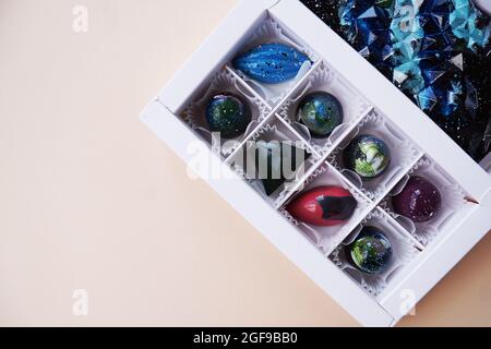 Scatola regalo bianca di cioccolatini fatti a mano. Design geometrico e spaziale. Su uno sfondo chiaro. Dolci e caramelle in primo piano Foto Stock