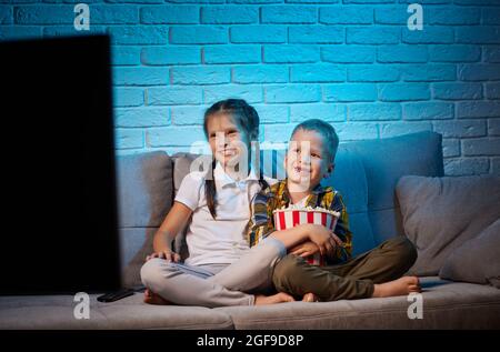 Due bambini con telecomando per guardare la TV Foto Stock