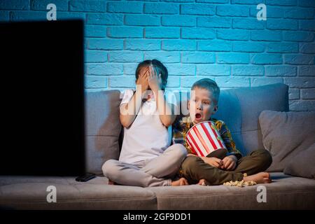 Due bambini con telecomando per guardare la TV Foto Stock