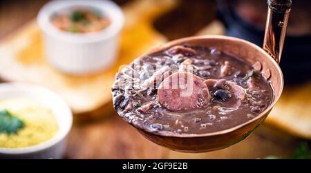 Feijoada, cucina brasiliana. Maiale con fagioli, salsiccia, cavolo e pepe Foto Stock