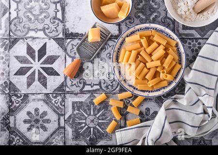 Pasta, pasta italiana. Rigatoni e verdure ingredienti di cottura su un vecchio sfondo di pietra. Ingredienti per la cucina italiana. Vista dall'alto con copy spa Foto Stock