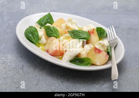 insalata di caprese alla pesca; pesca piatta, mozzarella e basilico Foto Stock