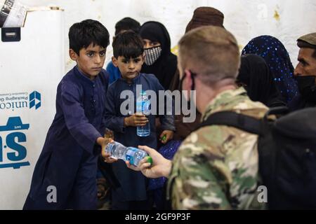 Aeroporto Ali al Salem, Kuwait. 22 agosto 2021. Una polizia militare dell'aeronautica degli Stati Uniti con la sedicesima brigata della polizia militare, consegna bottiglie d'acqua ai rifugiati afghani durante l'operazione Rifugi Alleati all'arrivo alla base aerea Ali al Salem 23 agosto 2021 ad Ali al Salem, Kuwait. Credit: Planetpix/Alamy Live News Foto Stock