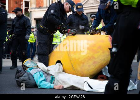LONDRA, INGHILTERRA - AGOSTO 24 2021, i manifestanti di Extinction Rebellion si incollano agli oggetti e alla terra a Cambridge Circus London Foto Stock