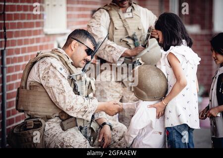 Kabul, Afghanistan. 24 agosto 2021. Una Marina statunitense assegnata alla Special Purpose Marine Air-Ground Task Force - Crisis Response team scuote le mani con un bambino che indossa il casco all'Aeroporto Internazionale Hamid Karzai durante l'operazione Allies Refuge 24 agosto 2021 a Kabul, Afghanistan. Credit: Planetpix/Alamy Live News Foto Stock