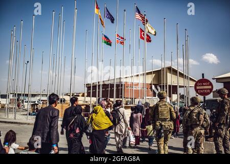 I soldati assegnati alla 82° Divisione Airborne accompagnano un gruppo di persone al terminal dell'aeroporto internazionale Hamid Karzai, 23 agosto. I membri del servizio degli Stati Uniti stanno assistendo il Dipartimento di Stato con un'operazione DI evacuazione non combatante (NEO) in Afghanistan. (STATI UNITI Foto del corpo marino di 1° Ora. Mark Andries) Foto Stock