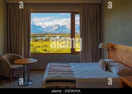 Camera d'hotel dal design classico con tende aperte e vista sul Cuernos del Paine, il parco nazionale Torres del Paine, Patagonia, Cile. Foto Stock