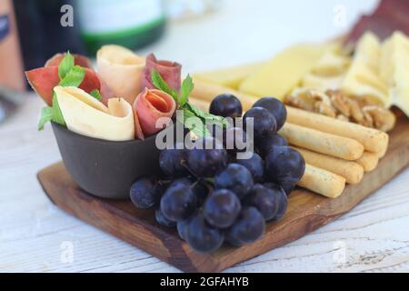Salumi italiani con cracker di formaggio e salumi serviti su tavola di legno con bordo di corteccia grezzo Foto Stock