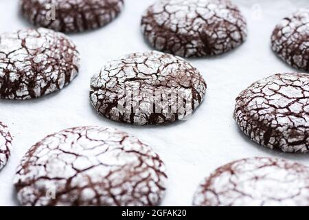 Biscotti crinkle di cioccolato fatti in casa in zucchero in polvere su una carta pergamena. Cibo sfondo. Messa a fuoco selettiva. Foto Stock