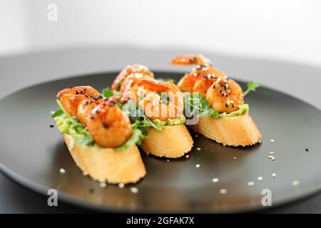 Bruschetta con gamberi, cosparso di semi di sesamo su un piatto, buffet con frutti di mare Foto Stock