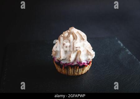 Muffin su sfondo nero. Su sfondo scuro, torte con ripieno di frutta su un piano di servizio nero in pietra. Foto Stock