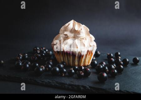 Muffin su sfondo nero con bacche di ribes. Su sfondo scuro, dolci con ripieno di frutta e bacche e ribes su un bos di servizio in pietra nera Foto Stock