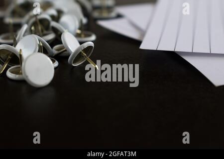 Materiale per ufficio come alcuni fogli di carta e altri articoli di cancelleria bianca su un tavolo di legno nero Foto Stock