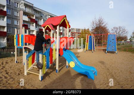 POZNAN, POLONIA - 01 novembre 2015: Una giovane mummia che aiuta suo figlio a camminare sulle scale dello scivolo del parco giochi a Poznan, Polonia Foto Stock