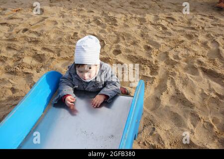 POZNAN, POLONIA - 01 novembre 2015: Un adorabile bambino da uno scivolo in acciaio inossidabile a Poznan, Polonia Foto Stock