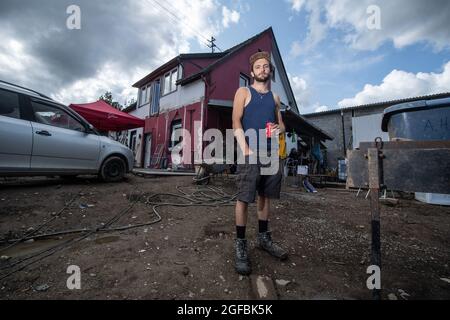 Schuld, Germania. 21 Agosto 2021. Tim Himmes si trova di fronte alla casa della sua famiglia a Schuld, che è stata gravemente danneggiata dall'alluvione. Lo showman di 21 anni sta cercando da settimane di liberare la casa di famiglia da fango e sporcizia in gran parte da solo. Allontanarsi non è un'opzione per il giovane, la sua famiglia ha vissuto nel piccolo villaggio sul fiume Ahr per decenni. (A dpa 'six settimane dopo l'alluvione: 'La regione ha bisogno di una prospettiva' dal 25.08.2021) credito: Boris Roessler/dpa/Alamy Live News Foto Stock