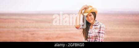 Donna di Cowgirl sorridente felice sul paesaggio di fattoria di paese che indossa cappello di cowboy. Bella giovane ragazza asiatica americana multirazziale in campagna panoramica Foto Stock