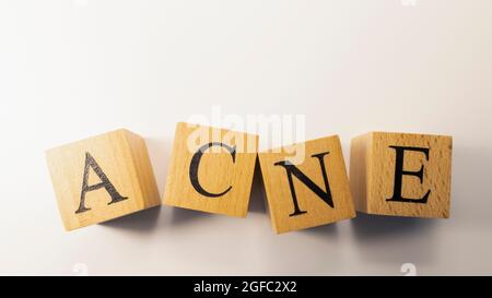 La parola acne è stata creata da cubi di legno, parentela e persone. Primo piano. Foto Stock