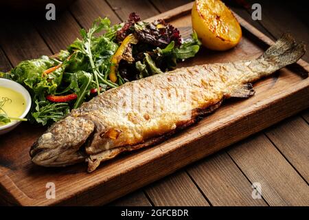 Pesce di trota fritto fatto in casa con salsa e insalata Foto Stock