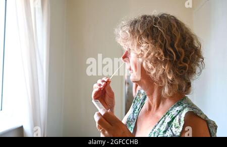 Una donna prende un test di flusso laterale del coronavirus COVID-19 a casa nel Regno Unito 2021 Foto Stock
