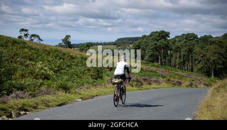 Ciclista maschile matura che attraversa la valle di Bowland, Lancashire, Regno Unito. Foto Stock