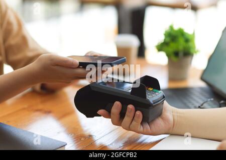 Primo piano, il cliente che paga le bollette utilizzando il codice QR scansione smartphone sul terminale di pagamento presso il bar, pagamento online, transazione di denaro Foto Stock