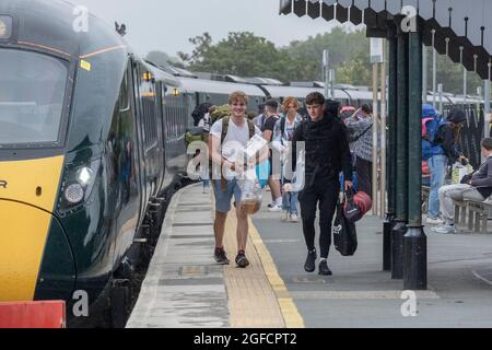 Giovani che arrivano alla stazione ferroviaria di Newquay per il giorno di apertura del festival Boardmasters in Cornovaglia. Foto Stock