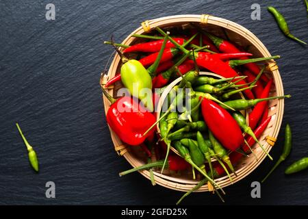 Assortimento di spezie alimentari peperoni peperoni in vimini di bambù su cartone di pietra ardesia nera con spazio copia Foto Stock